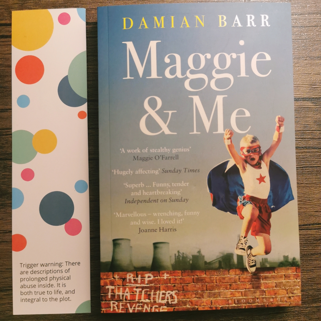 Photograph of a paperback copy of Maggie & Me with a themed bookmark. There is text at the bottom of the bookmark: "Trigger warning: There are descriptions of prolonged physical abuse inside. It is both true to life, and integral to the plot."